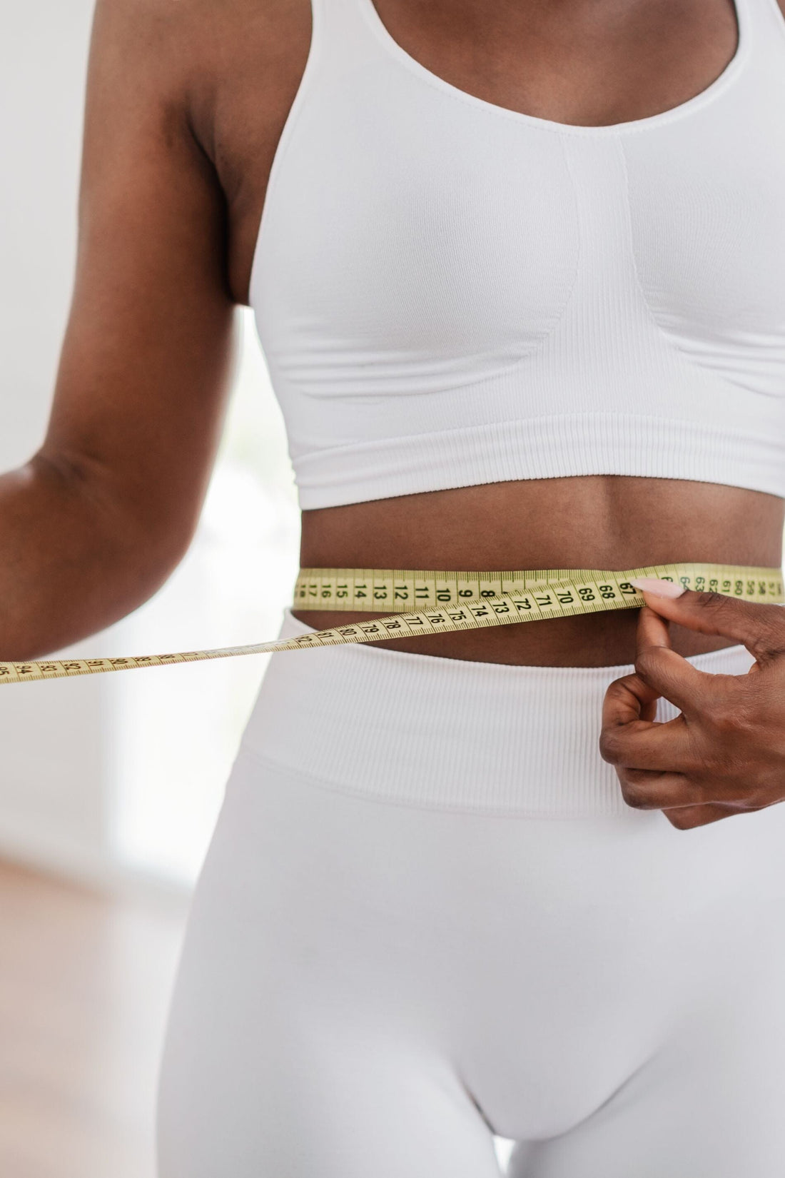 Woman measuring waist with measuring tape