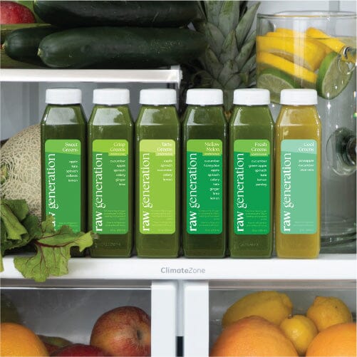 Bottles of green juice with white labels in a refrigerator, featuring fresh produce like apples and citrus, highlighting vegan and natural nutrition options.